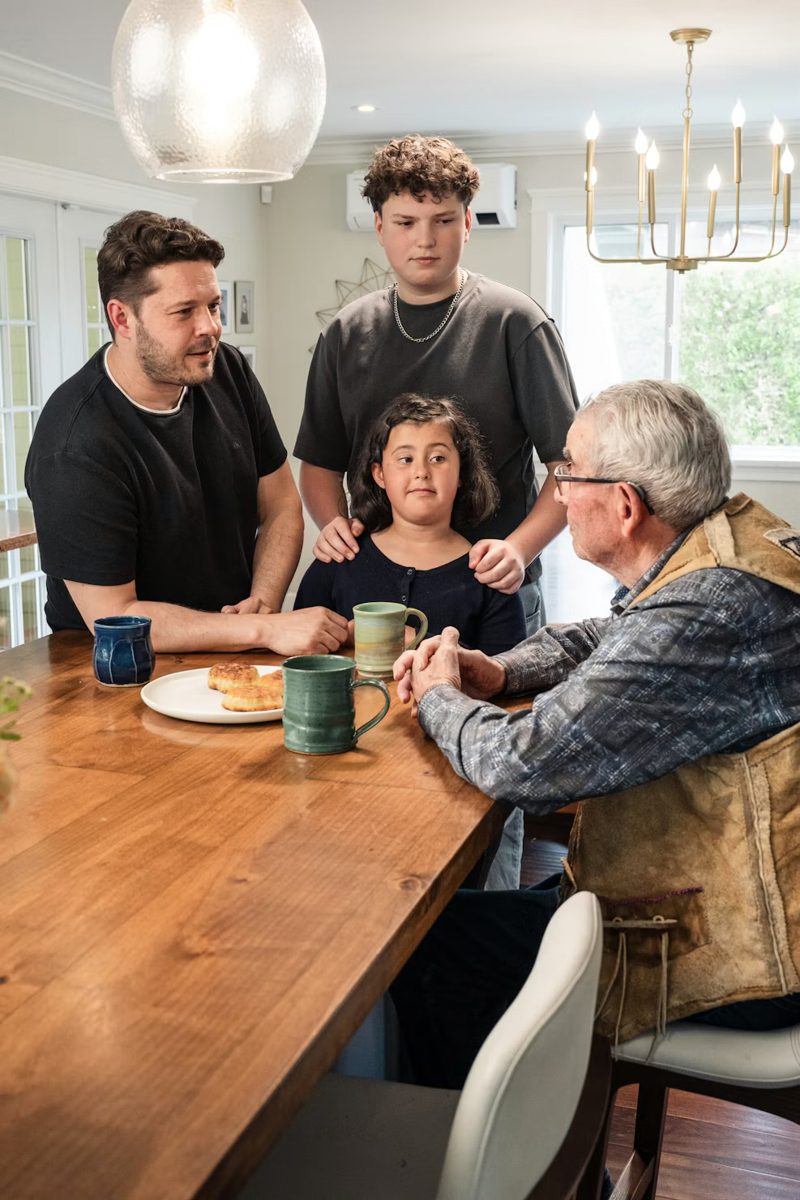 Three generations of a family talking around a kitchen table